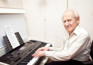 Smiling pleased senior man playing piano